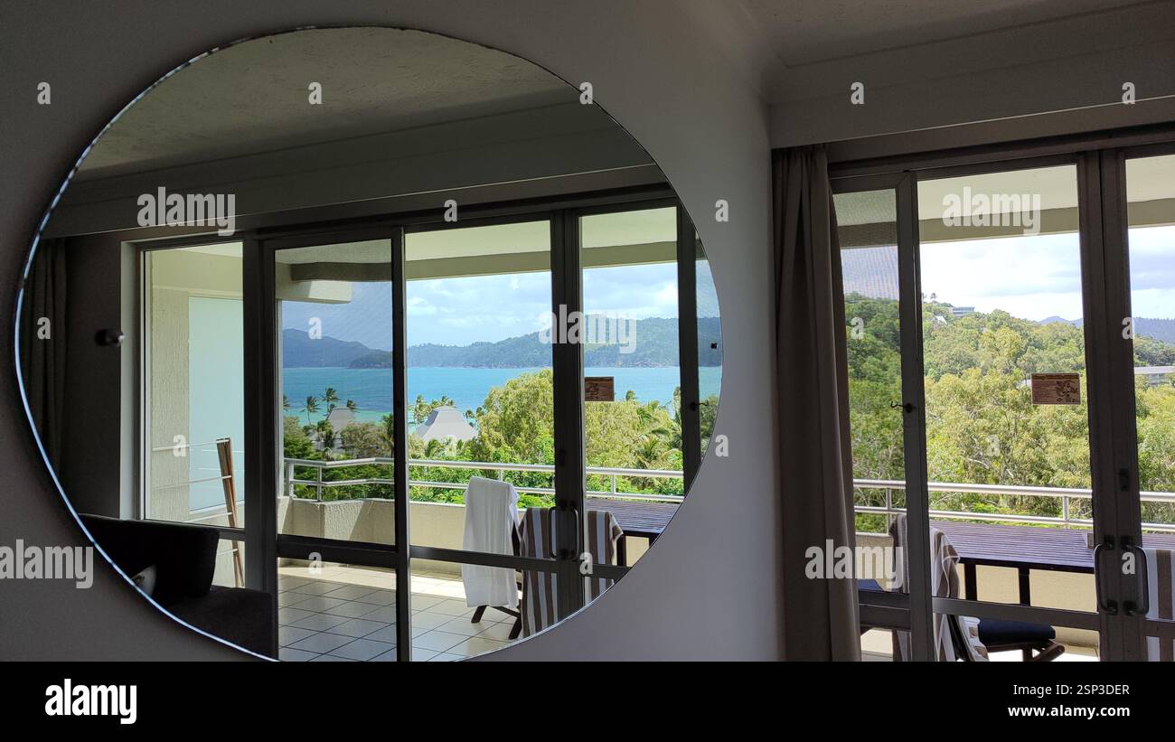 Illusione di Hamilton Island: Un balcone riflette l'oceano turchese sottostante, creando un coinvolgente gioco di luce e acqua. Foto Stock
