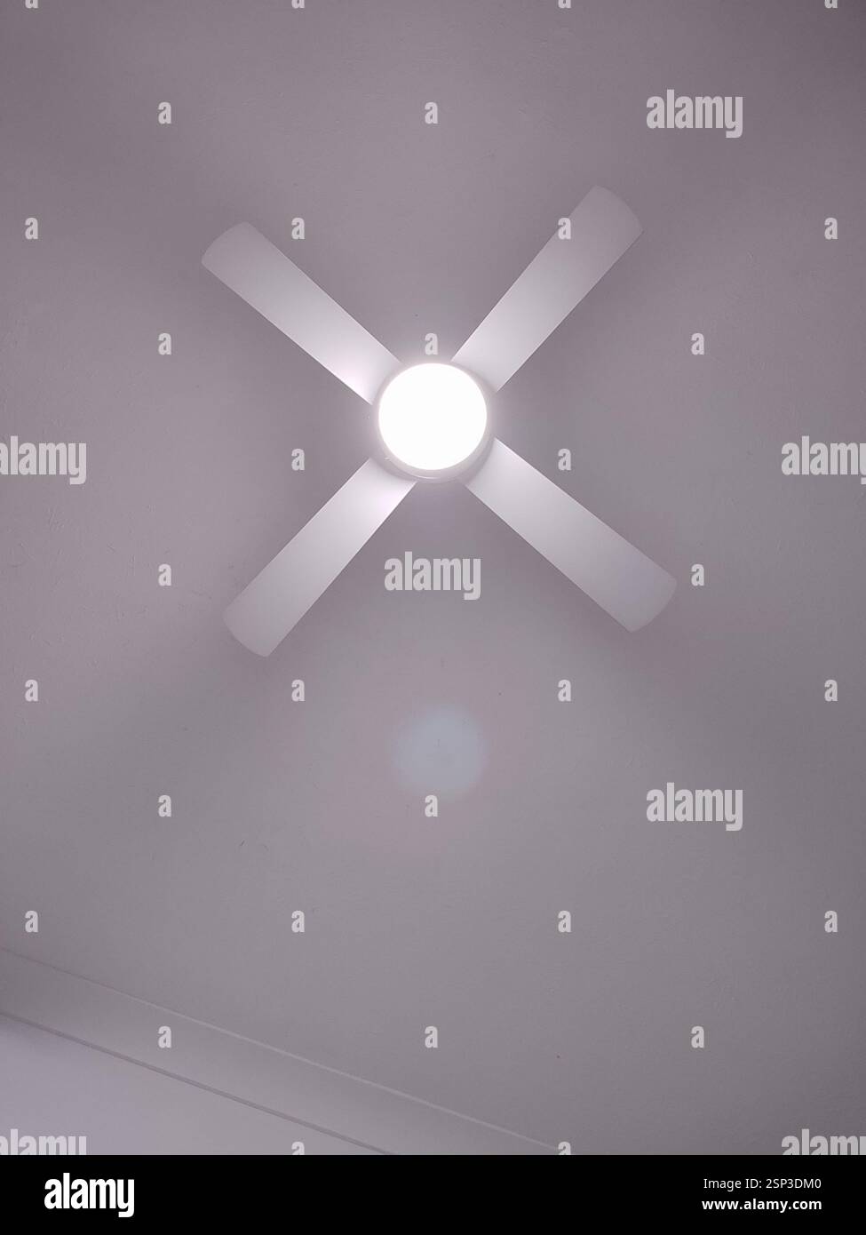 Ventilatore a soffitto Hamilton Island con quattro pale bianche e una lampada rotonda al centro. Il ventilatore è montato su un soffitto bianco. La luce è accesa e. Foto Stock
