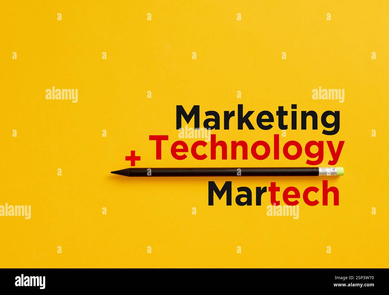 Matita nera che separa le parole di marketing e tecnologia, riassumendole in martech su sfondo giallo Foto Stock
