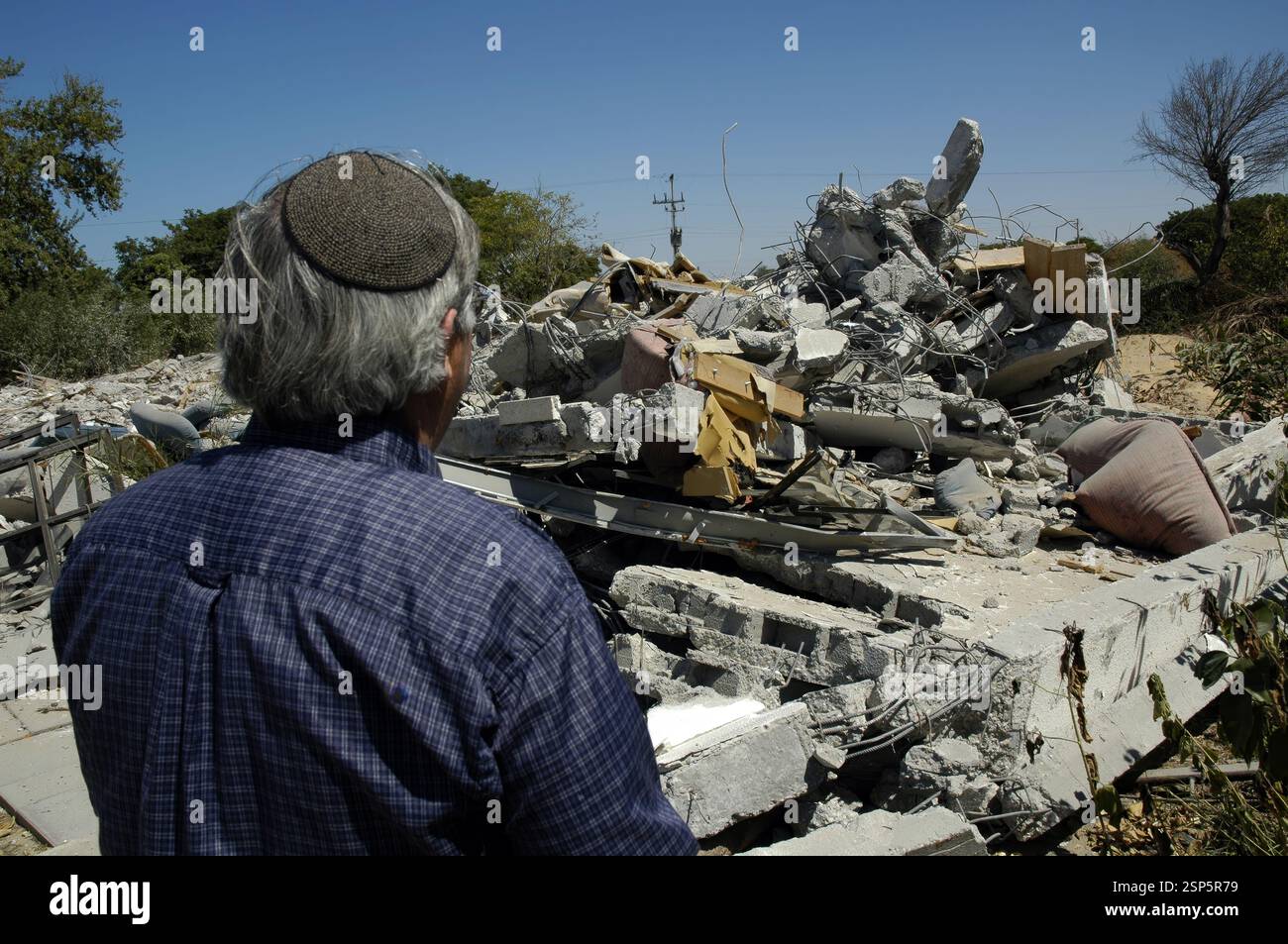 Un colono ebreo guarda i tumuli di macerie della sua casa demolita in quello che un tempo era l'insediamento israeliano di neve Dekalim il 21 agosto 2005. Circa 1700 case di coloni evacuate furono demolite nella Striscia di Gaza prima che le forze militari israeliane fossero fuori dall'area a metà settembre 2005, completando un ritiro dal territorio dopo 38 anni di occupazione Foto Stock