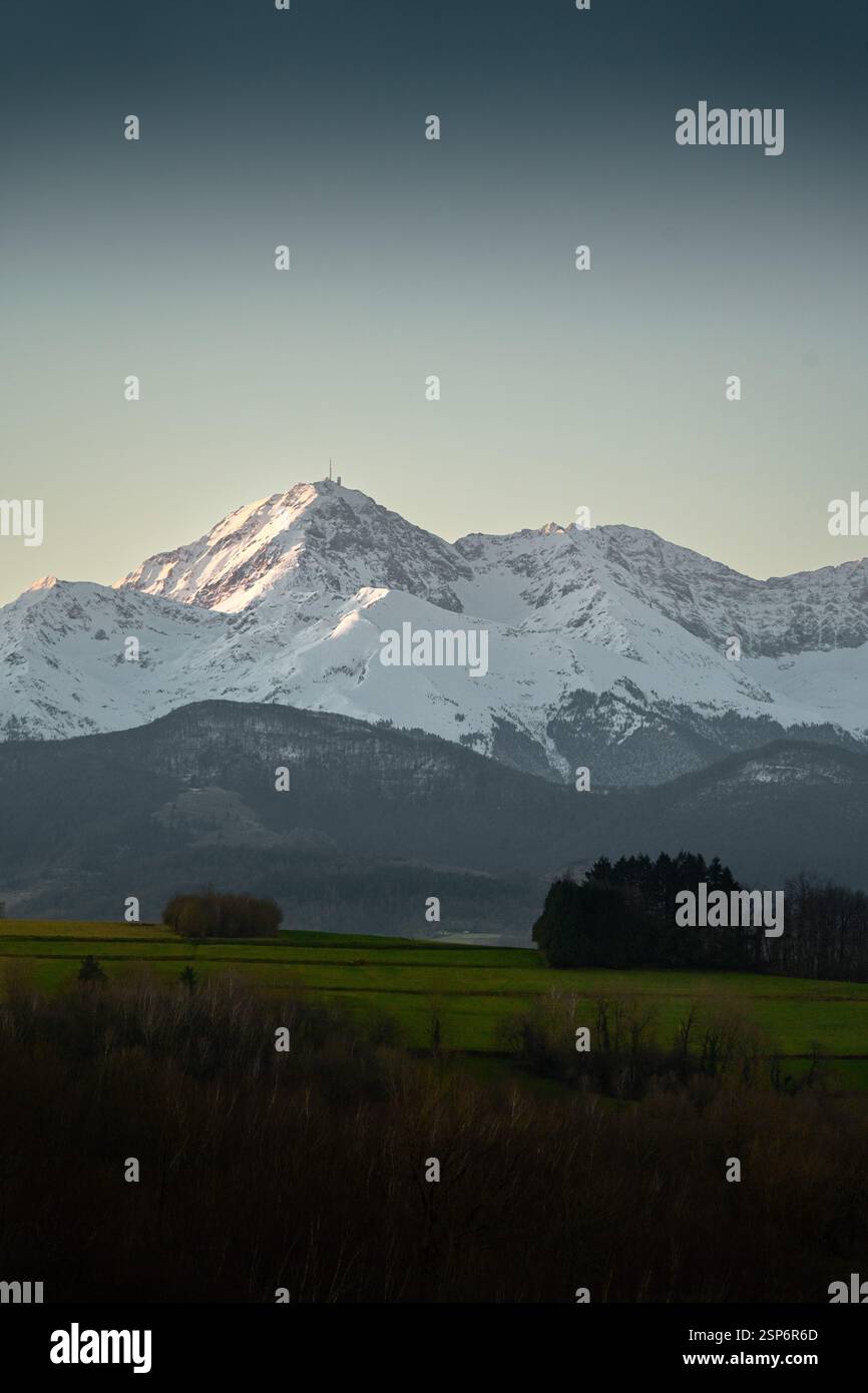 Francia, Hautes-Pyrénées. Il PIC du Midi de Bigorre, con il suo famoso osservatorio, sorge sopra la verde valle, ancora in parte all'ombra del m Foto Stock