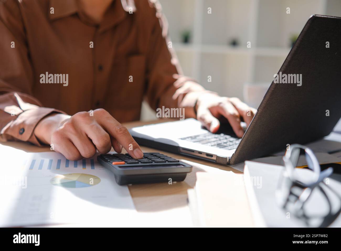Contabile che lavora sui calcoli finanziari utilizzando una calcolatrice Foto Stock
