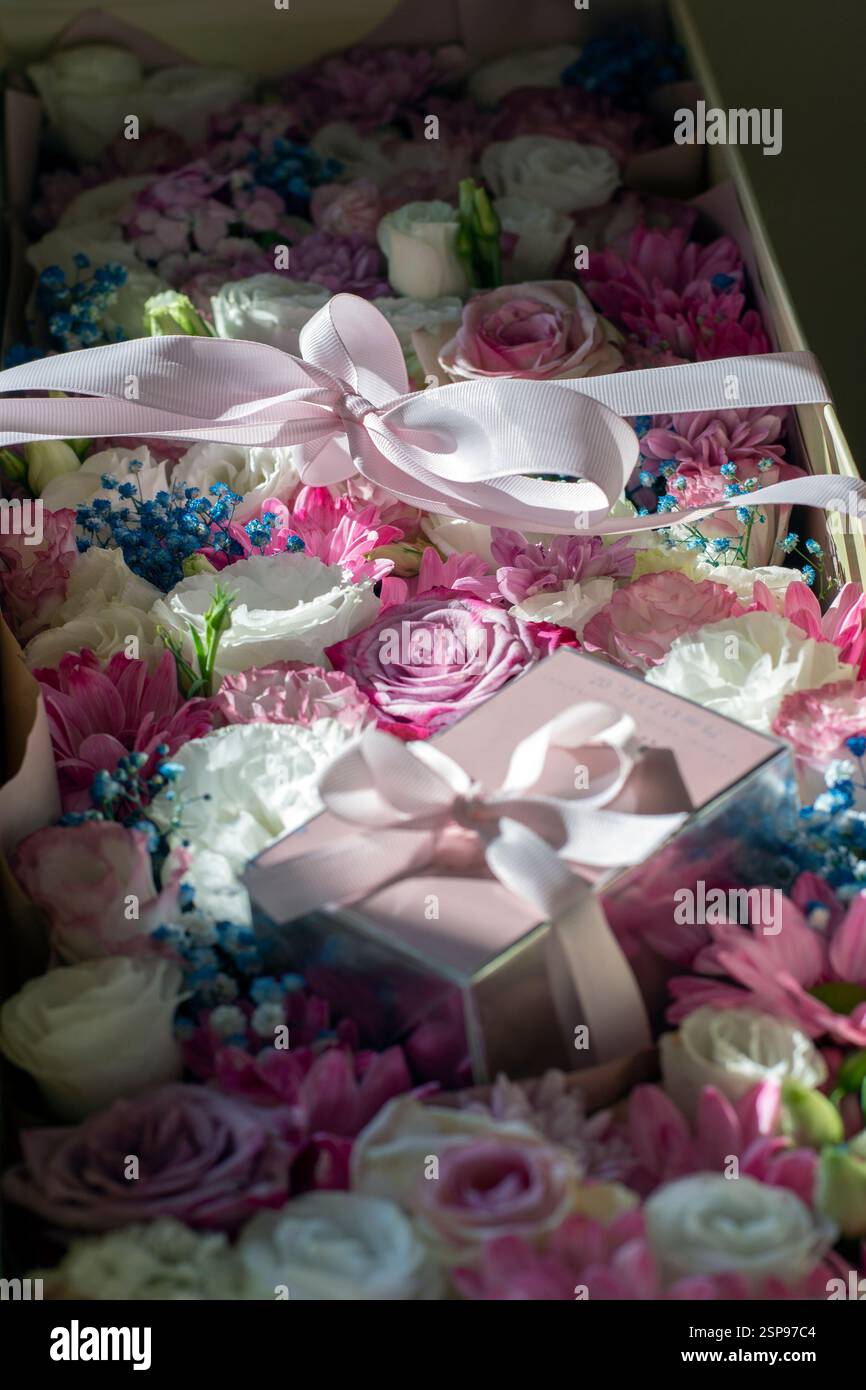 Confezione regalo con fiori e profumo avvolta in un nastro rosa Foto Stock