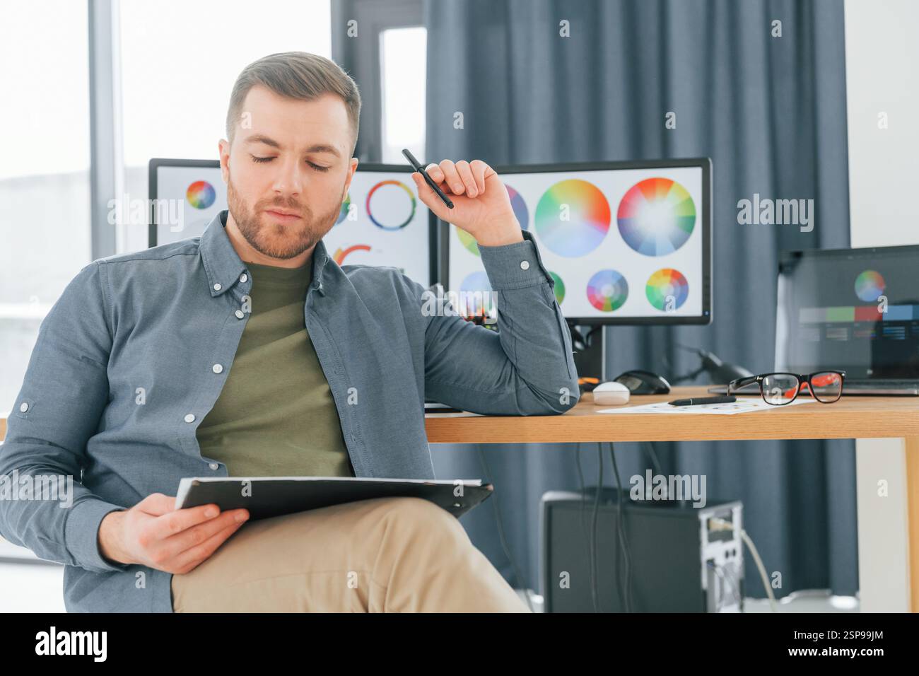 Con il tablet in mano. Progettista maschile che lavora in ufficio utilizzando un PC. Foto Stock
