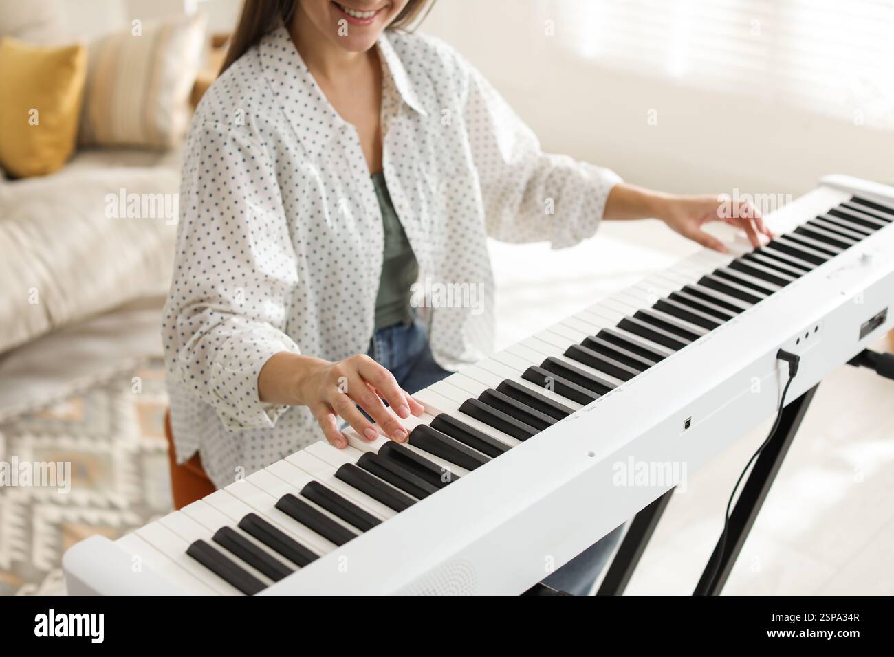 Donna sorridente che gioca a sintetizzatore a casa, primo piano Foto Stock