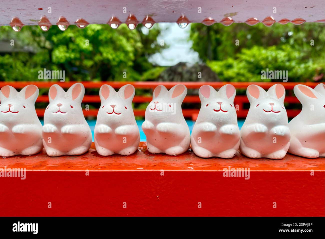 Amuleti di conigli di porcellana arroccati su una mensola rossa in un tempio di Kyoto. Foto Stock