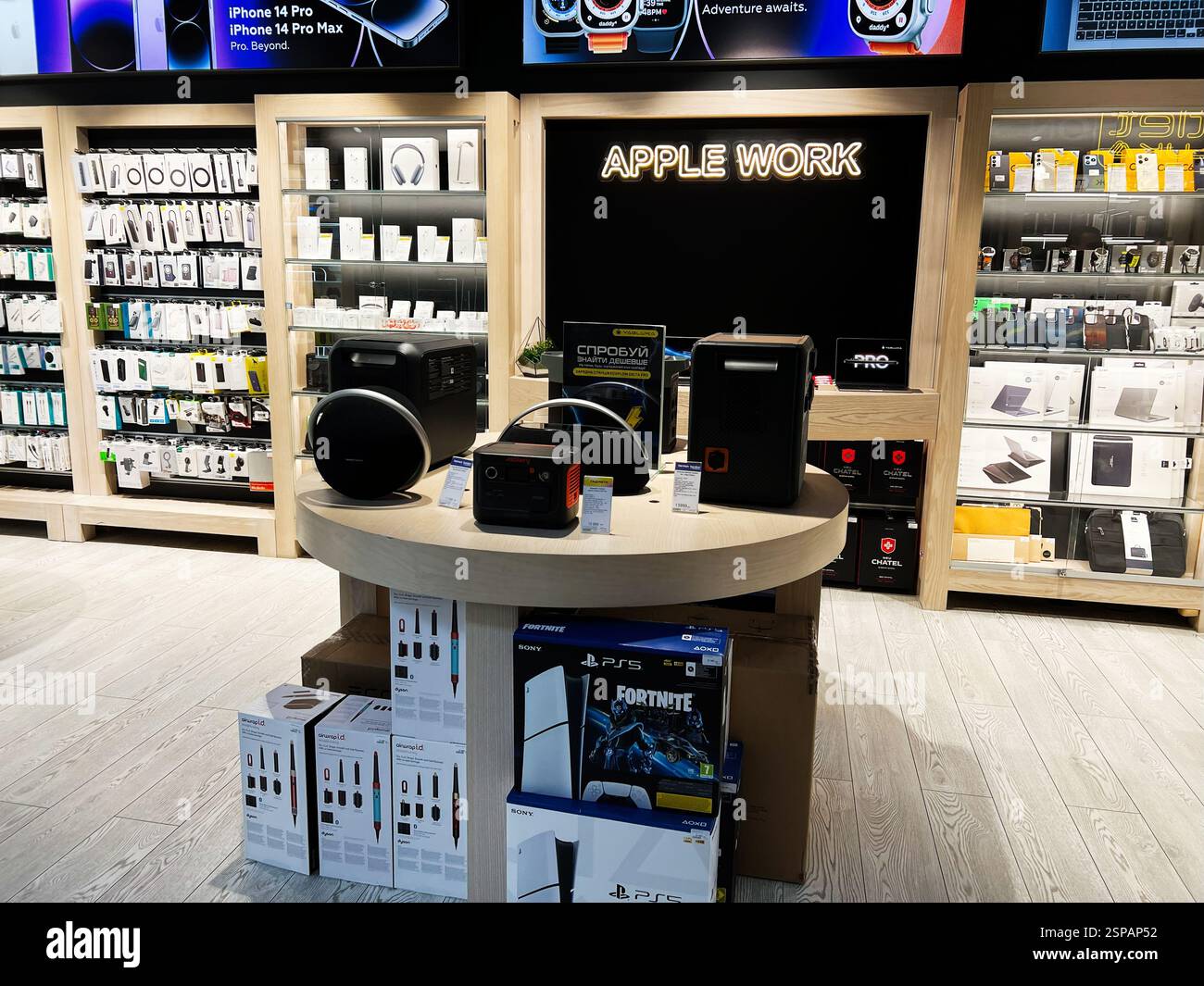 Leopoli, Ucraina - 13 febbraio 2025: Vari prodotti tecnologici e gadget esposti in un negozio al dettaglio Apple Work organizzato e illuminato Foto Stock