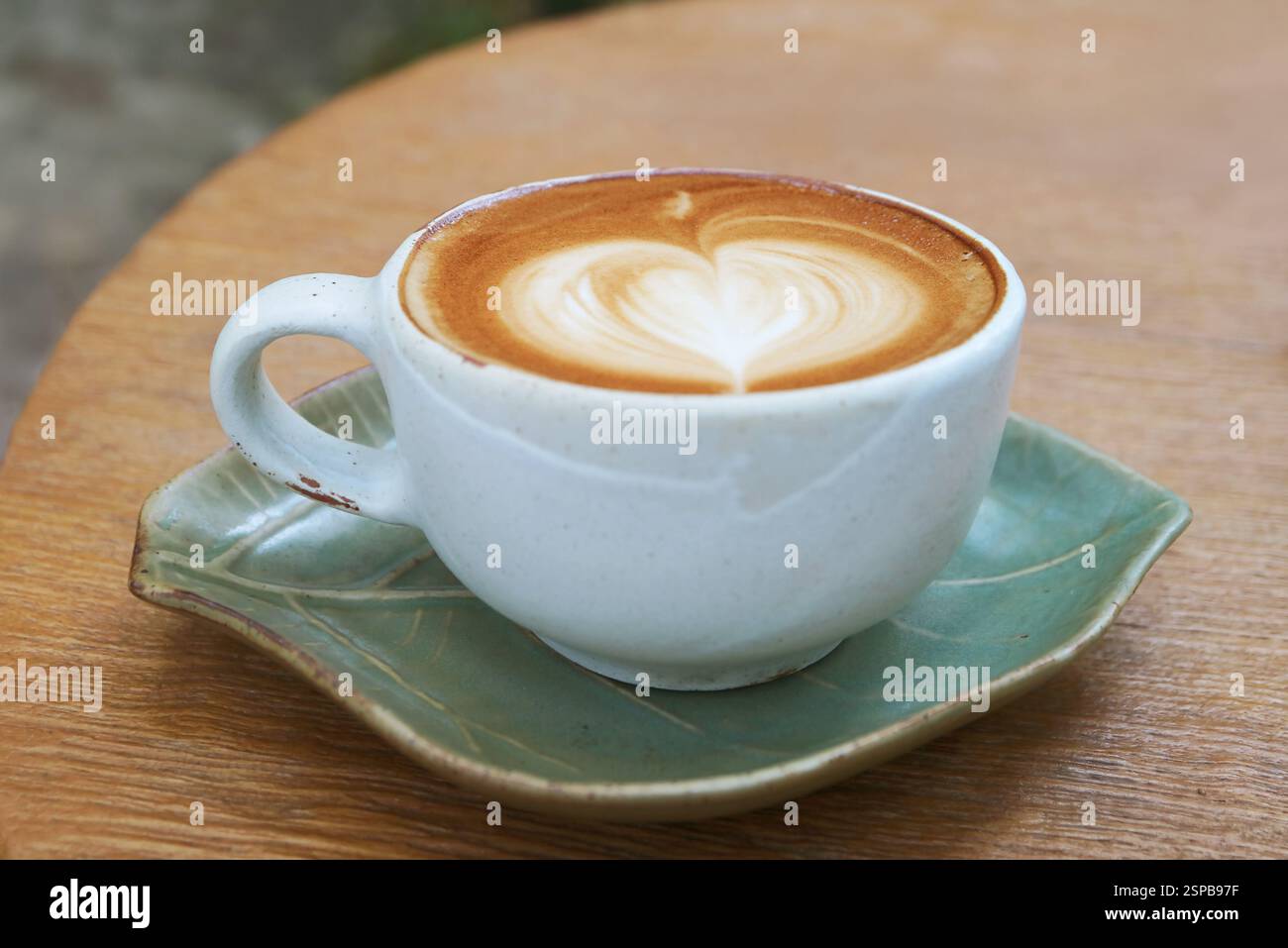 Una tazza di cappuccino con latte art a forma di cuore isolato su tavolo di legno Foto Stock