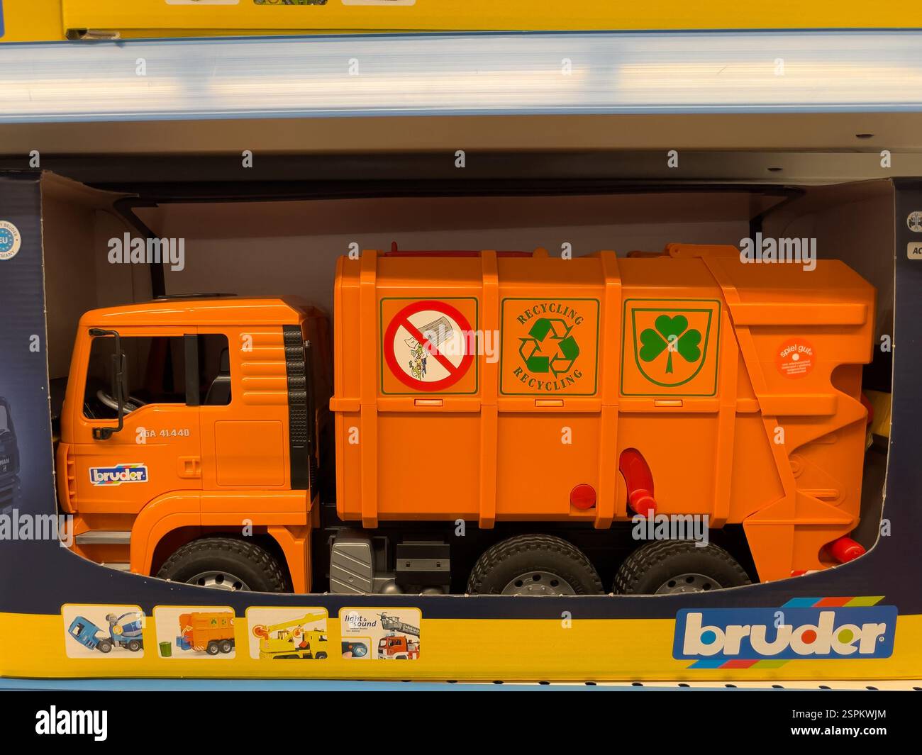 Spazzatura giocattolo arancione Bruder in una scatola. Il dumper è dotato di simboli di riciclaggio e di una shamrock. La confezione mostra le funzioni aggiuntive del giocattolo. Foto Stock