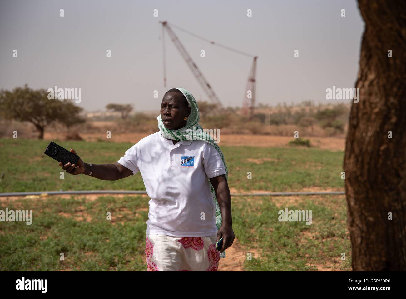 Mainouna Badian posa in un campo a Diogo, situato tra Dakar e Saint-Louis, nella regione di Thies in Senegal, il 20 dicembre 2024. È qui, proprio alle sue spalle, che l'esplorazione iniziò nel 2006 e poi nel 2014 lo sfruttamento di una delle più grandi miniere di zircone e ilmenite del mondo da parte della società senegalese grande Cote Operation SA (GCO*). Maimouna possedeva un campo a conduzione familiare dove praticava giardinaggio su 6-10 ettari e che doveva vendere per la modesta somma di 3,5 milioni di franchi CFA. (Circa 5350 euro) in una zona in cui di solito l'ettaro viene negoziato tra il 1,5 e. Foto Stock