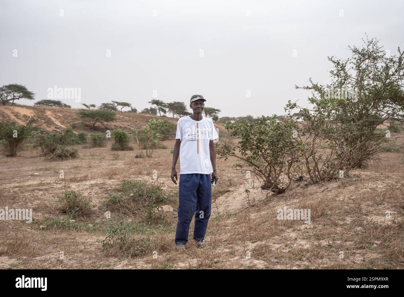 Abou Ka, che ha lavorato per 14 anni come guardia di sicurezza a ERAMET GCO, ci mostra la terra incoltivabile che lui e il suo parente (Ka Moussa) hanno ereditato a Foth, il 22 dicembre 2024. Il terreno povero e il difficile accesso all'acqua a causa della profondità della trivellazione che si dovrebbe realizzare rendono praticamente impossibile il giardinaggio del mercato. Molti residenti dei villaggi di reinsediamento di Foth hanno dovuto rassegnarsi ad abbandonare il loro lavoro nei campi. Oggi, Abou Ka svolge piccoli compiti quotidiani come bruciare spazzatura nel villaggio per 1000 franchi CFA al giorno. (1,5 euro) - 22/12/2024 - Senegal / Foto Stock