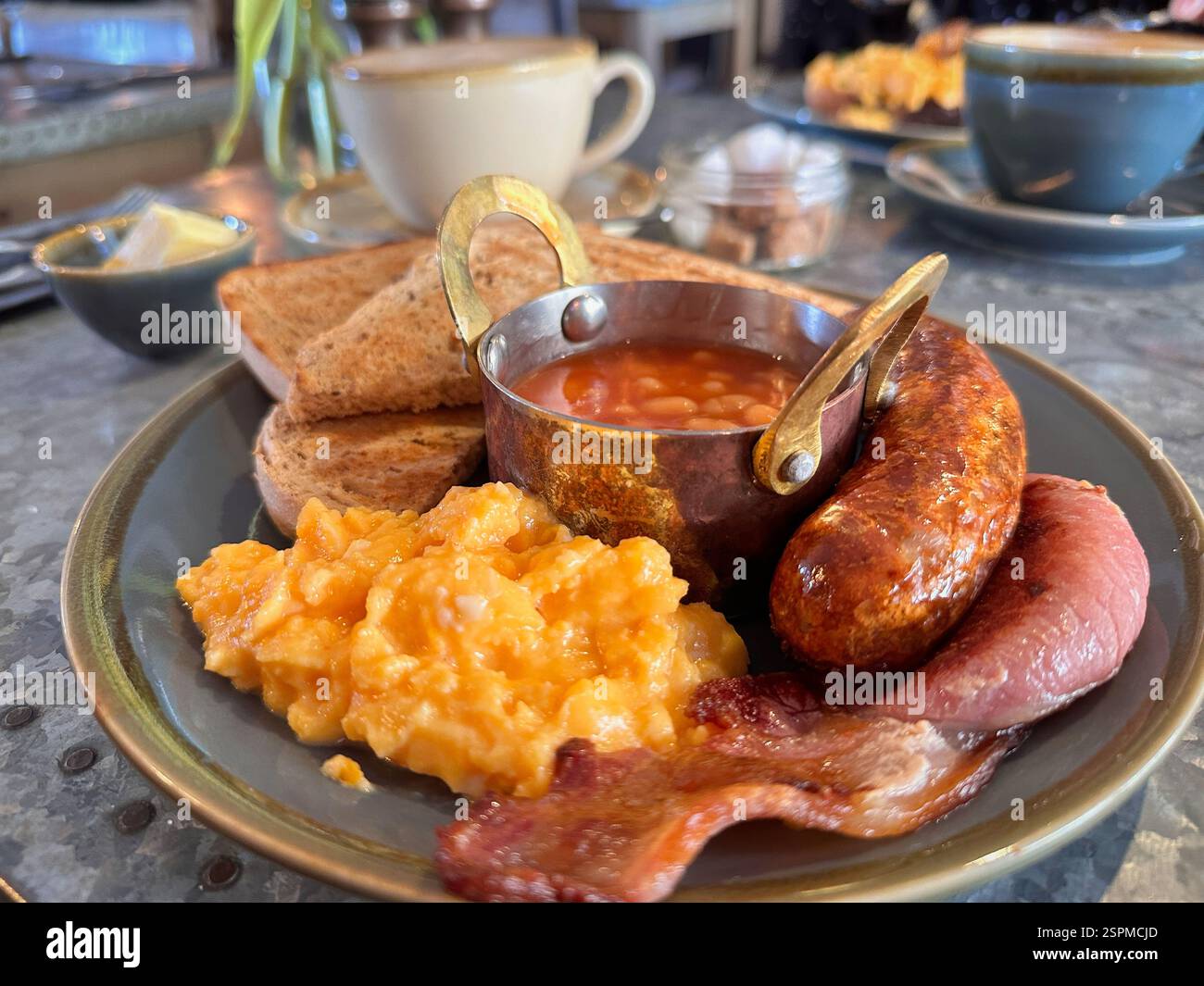 Deliziosa colazione all'inglese completa con salsiccia, pancetta, fagioli al forno, uova strapazzate e pane tostato Foto Stock