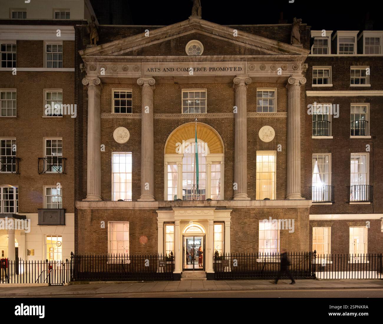 The Institute of Art and Commerce (ISA), 50-52, Great Portland Street, Londra, di notte. Le persone sono fuori dall'edificio. Foto Stock