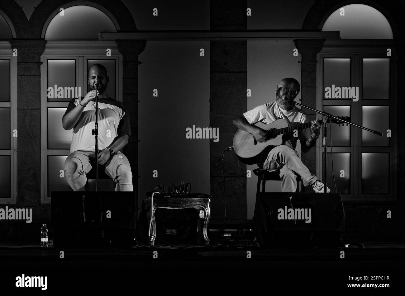 I musicisti locali si esibiscono in una piazza della città di notte, uno canta e l'altro suona la chitarra Foto Stock