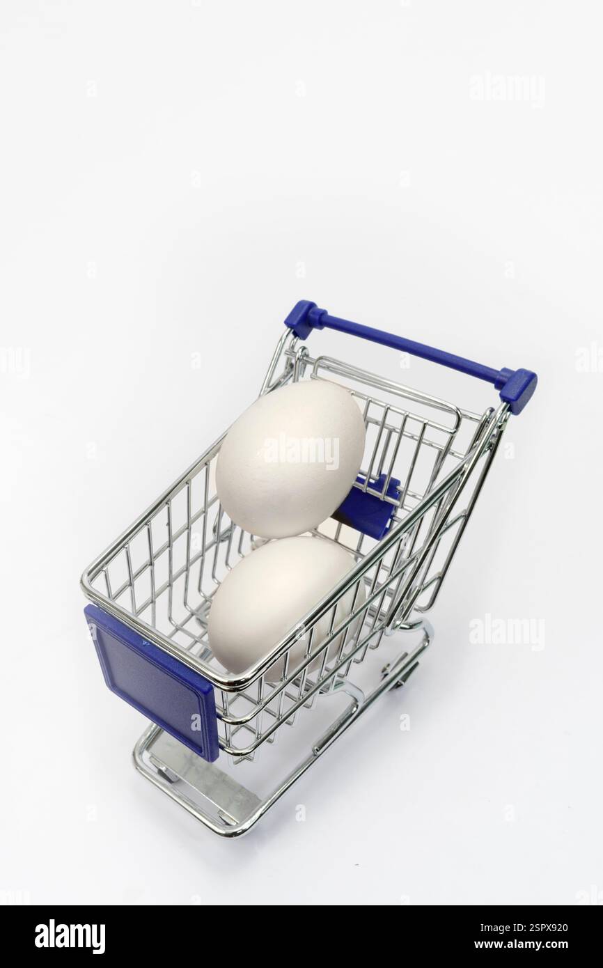 Shot verticale di due uova bianche in un piccolo carrello su bianco con spazio per le copie. Foto Stock