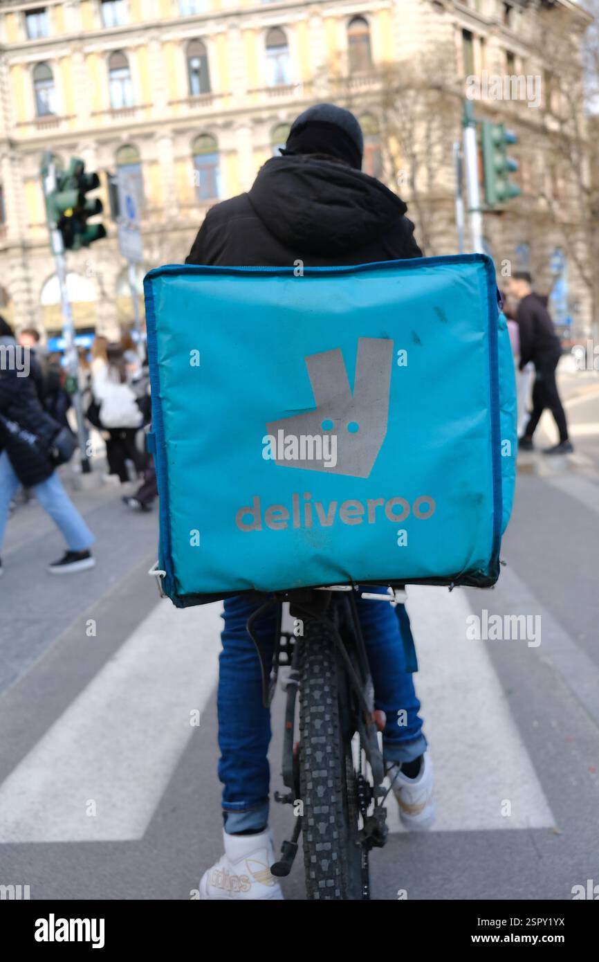 Dipendente del servizio di consegna che effettua la consegna, Deliveroo a Milano, Italia Foto Stock