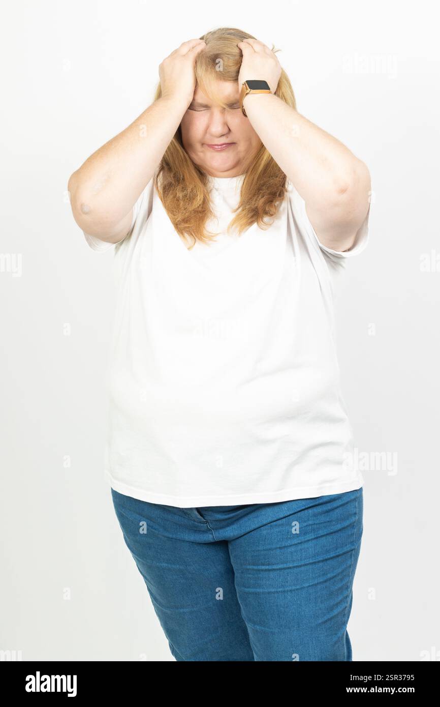 Ritratto di una donna adulta che tiene la testa con entrambe le mani, mostrando segni di angoscia e dolore. Foto Stock