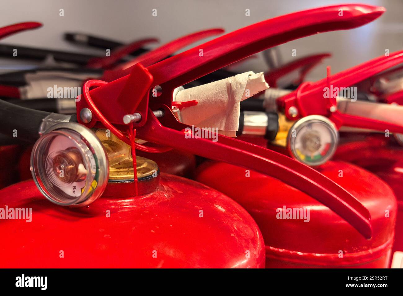 Gli estintori di colore rosso brillante sono disposti in modo ordinato su un ripiano, con ugelli metallici ed etichette di ispezione. Questa installazione prepara i volontari per e. Foto Stock