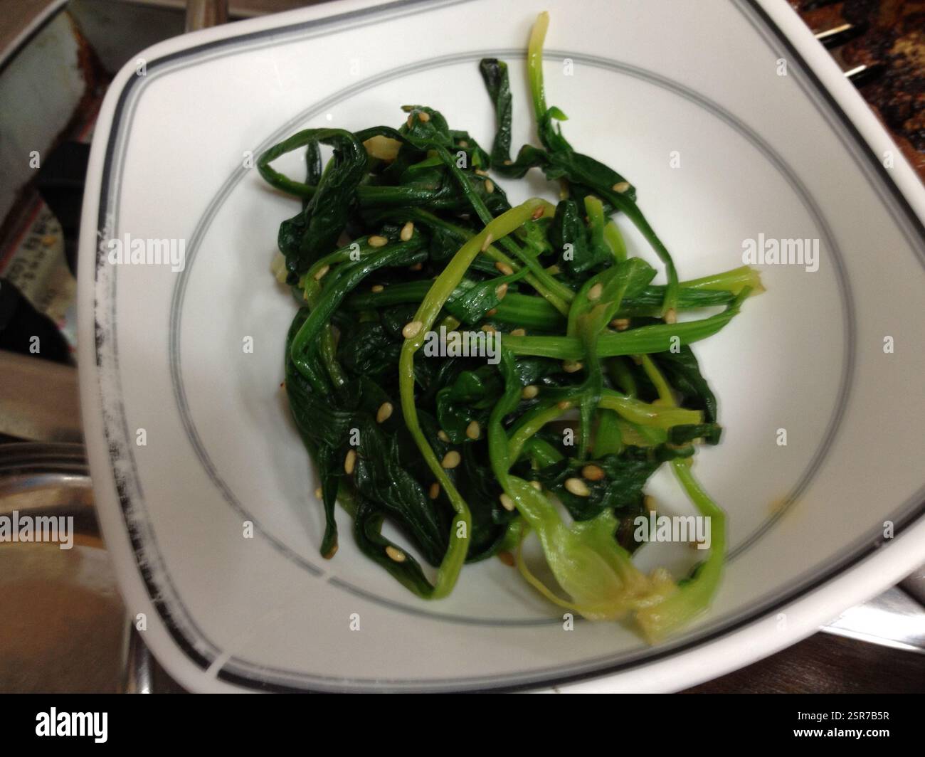 Coreano Spinach Namul. Semi di sesamo cosparsi su foglie di spinaci selvaggi. Un popolare contorno coreano con un gusto leggermente amaro e salato. Questa immagine Foto Stock