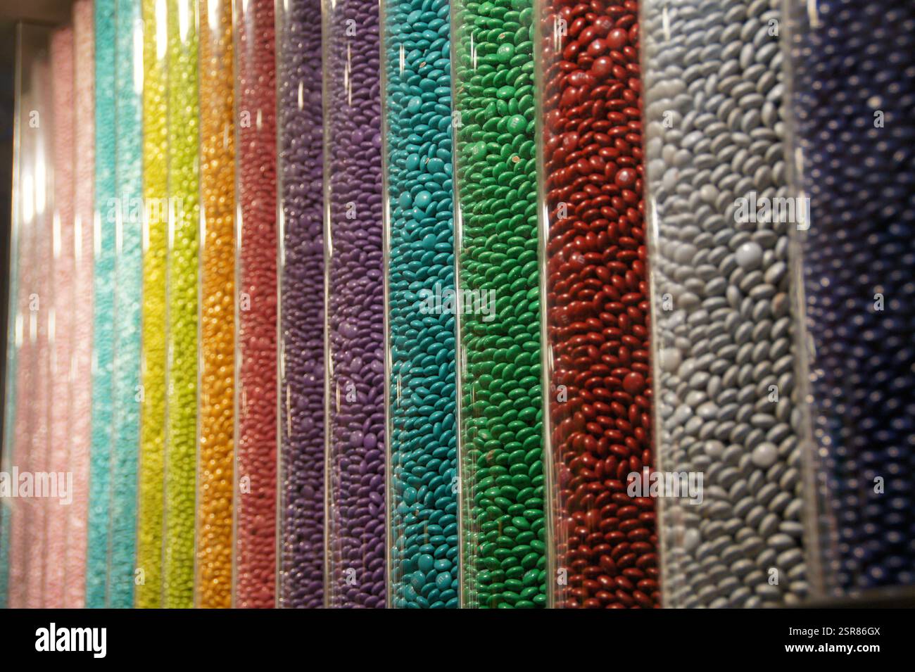 New York, Manhattan. I tubi acrilici scoppiano con M&M in un affascinante arcobaleno. I colori vivaci, meticolosamente disposti, creano una deliziosa caramella Foto Stock