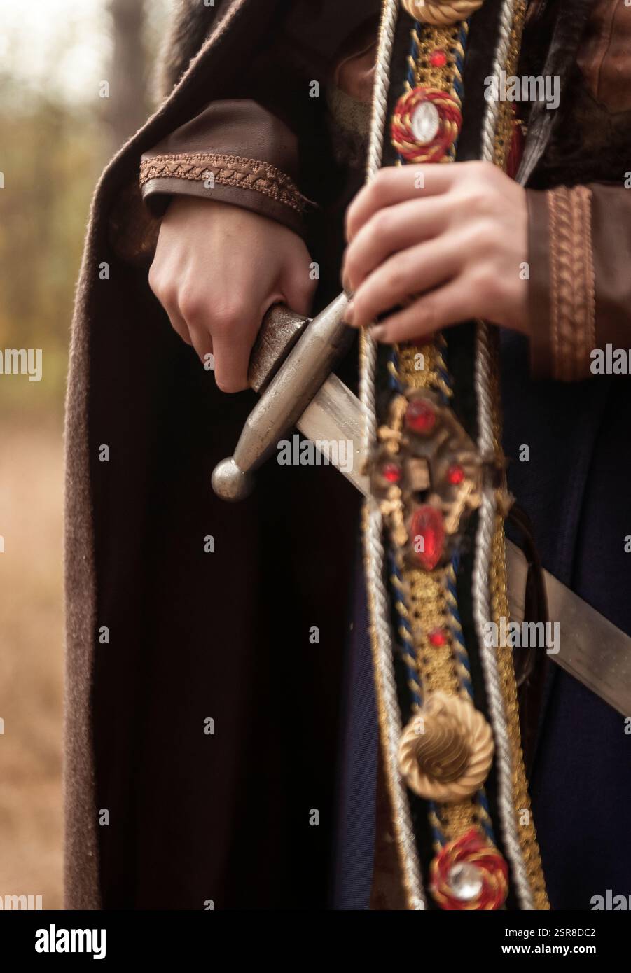 primo piano di una spada e della sua guaina. mani femminili che tengono una spada, niente faccia Foto Stock
