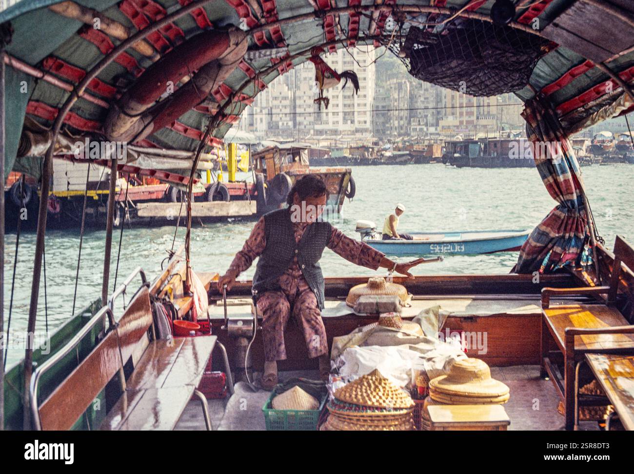 Donna cinese che indossa un tradizionale cappello di bambù che guida una barca turistica sampan, offrendo gite in barca ai turisti nel porto di Aberdeen, Hong Kong, Asia. Foto d'archivio scattata nel 1991 Foto Stock