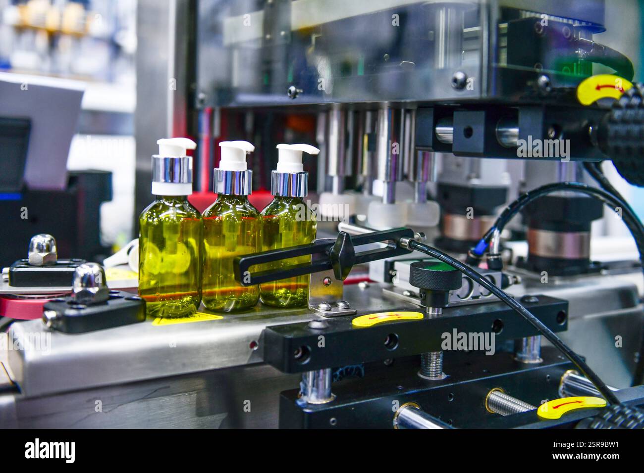 Bottiglie di vetro in un nastro trasportatore su una macchina di riempimento verticale automatica di alta qualità. Nella linea di produzione della fabbrica Foto Stock