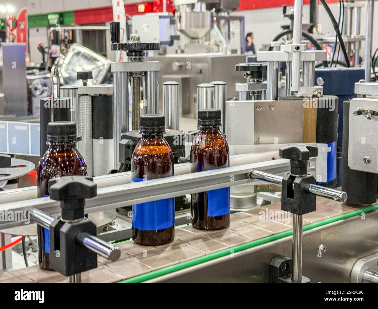 Bottiglie di vetro in un nastro trasportatore su una macchina di riempimento verticale automatica di alta qualità. Nella linea di produzione della fabbrica Foto Stock