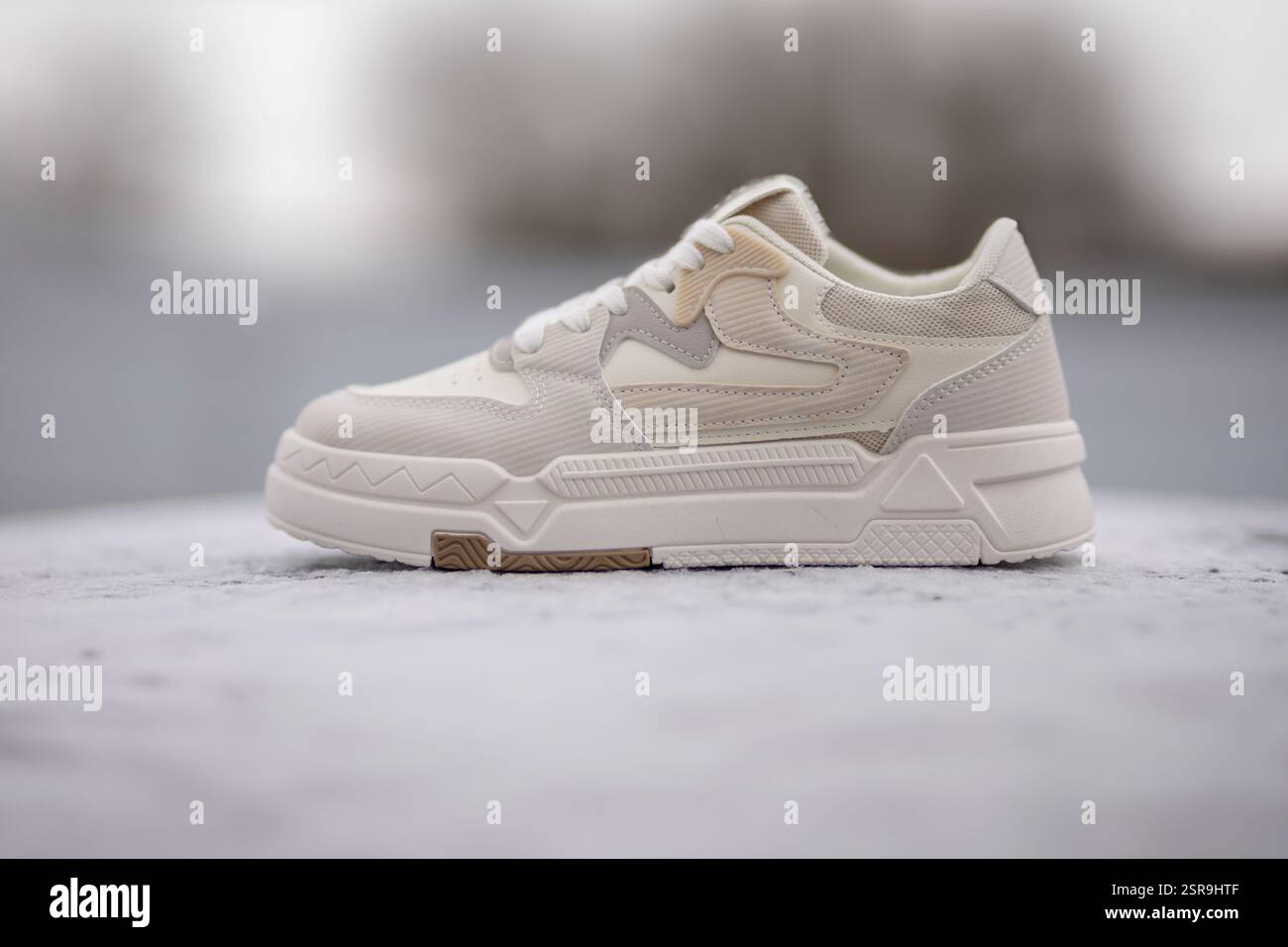 Sneaker bianca moderna che presenta un design e una texture unici su una superficie in cemento Foto Stock