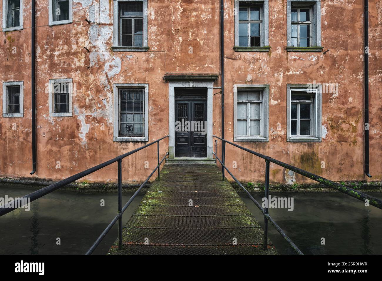 Facciata di un vecchio edificio abbandonato che si affaccia su un canale. Degrado urbano. Udine, Friuli Venezia Giulia, Italia Foto Stock