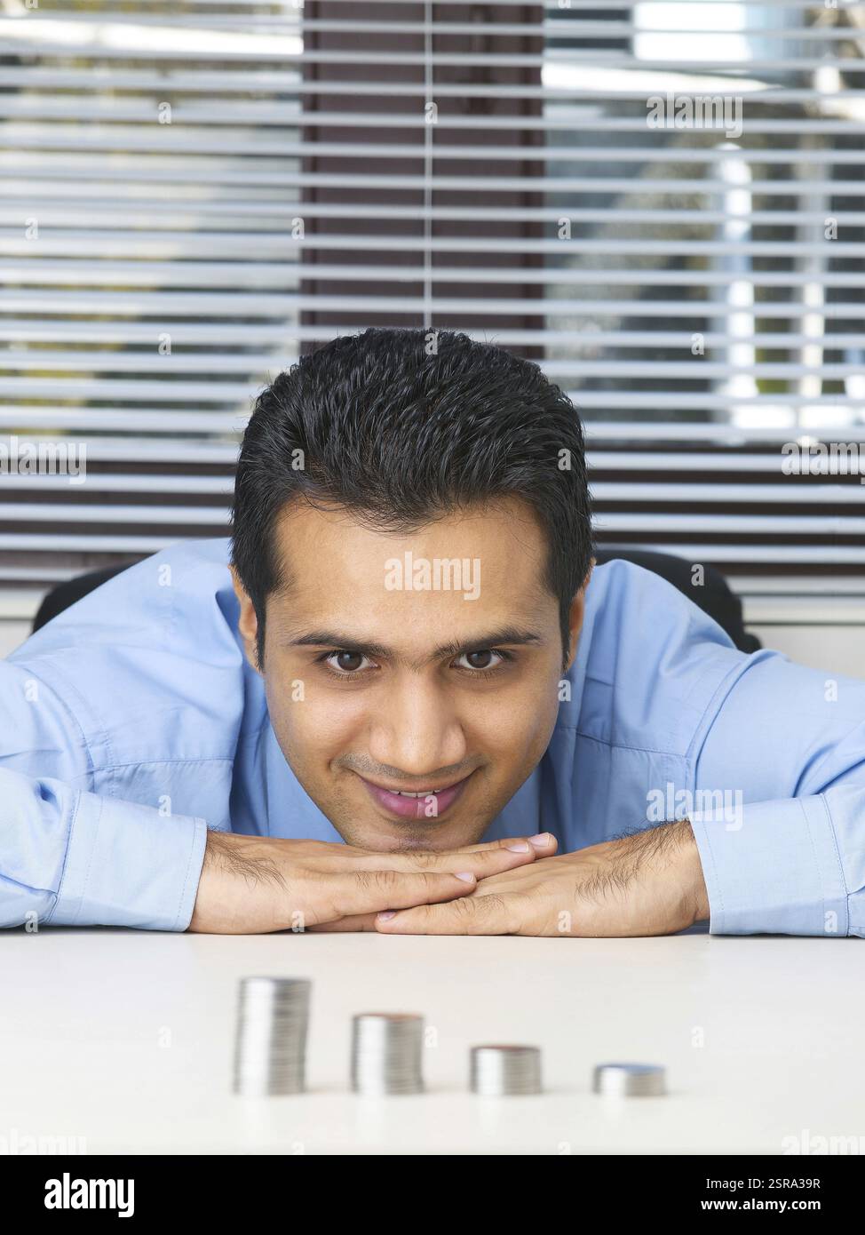 Executive toccando mento su entrambi le mani osservando mucchio di monete signor #779K Foto Stock