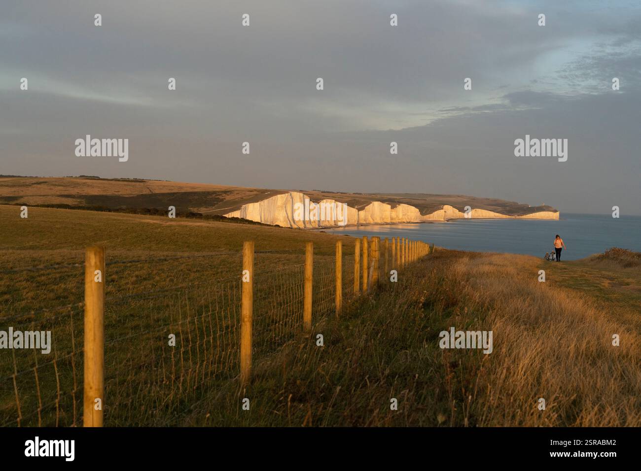 La persona cammina lungo le scogliere Seven Sisters al tramonto, East Sussex, Inghilterra. Foto Stock