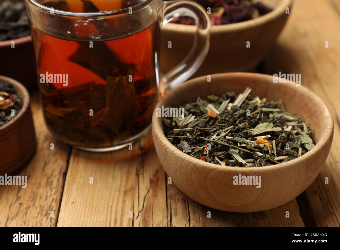 Tè aromatico e foglie secche su un tavolo di legno, primo piano Foto Stock