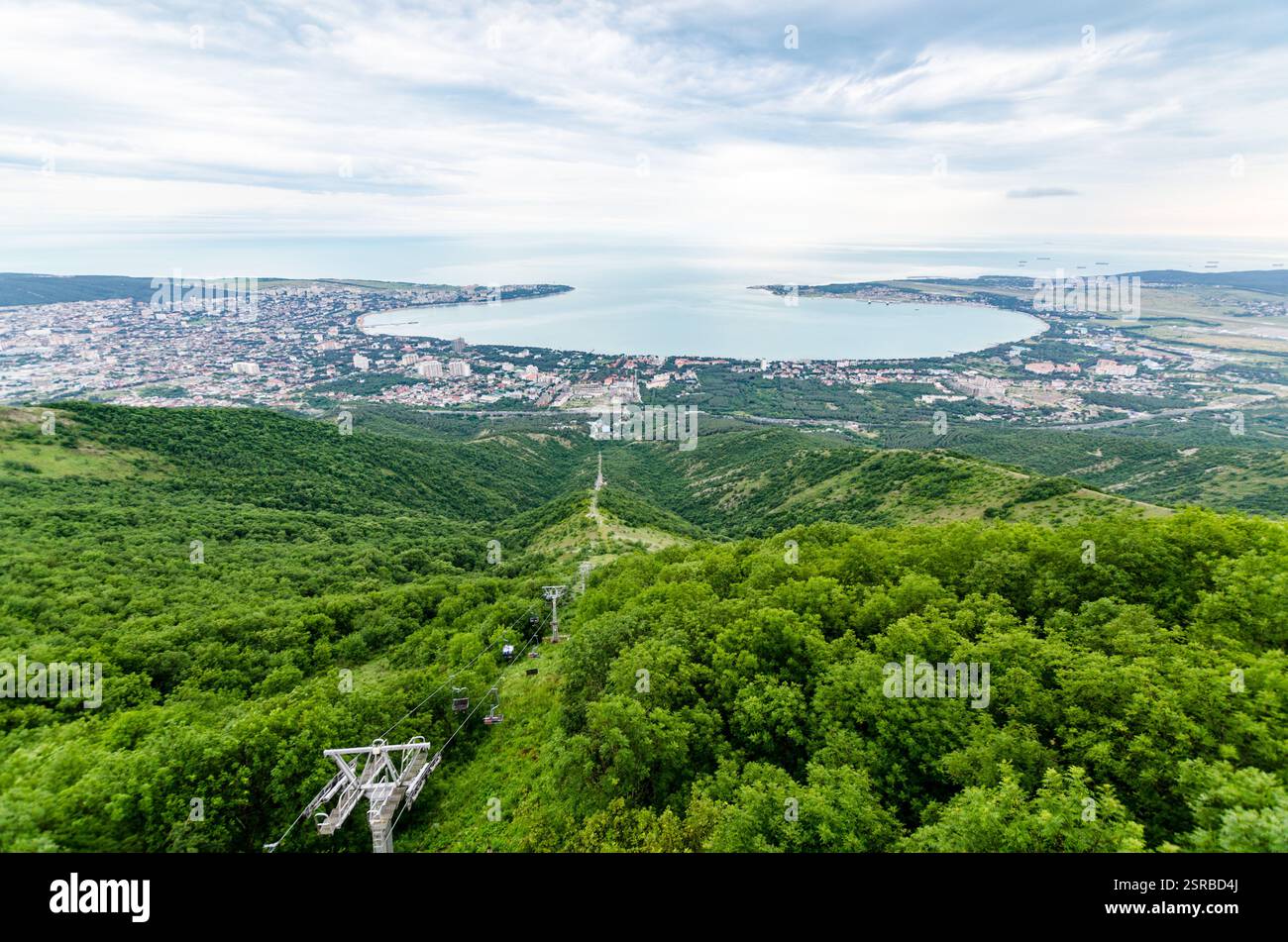 La splendida prospettiva aerea di Gelendzhik mostra una vegetazione lussureggiante, un mare blu tranquillo e un'affollata cittadina costiera. Le funivie scivolano sulle colline verdeggianti durante la guerra Foto Stock