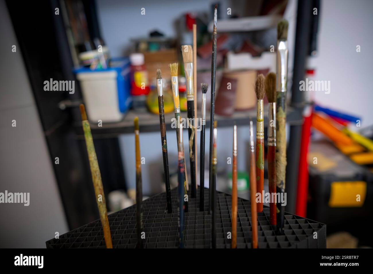 Diversi pennelli insieme, diverse dimensioni con segni di usura e macchie di vernice, scena di un laboratorio artistico. Foto Stock