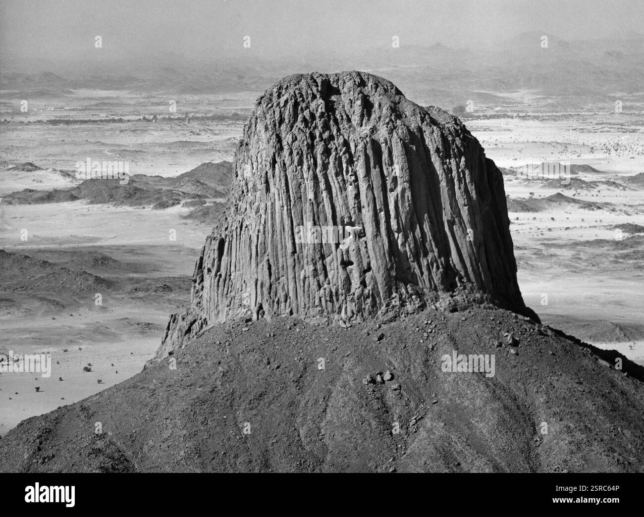 Ansicht der Felsformation PIC Laperina im Hoggar-Gebirge, die sich aus einer trostlosen Wüstenlandschaft erhebt, Sahara 1970 Jahre. Foto Stock