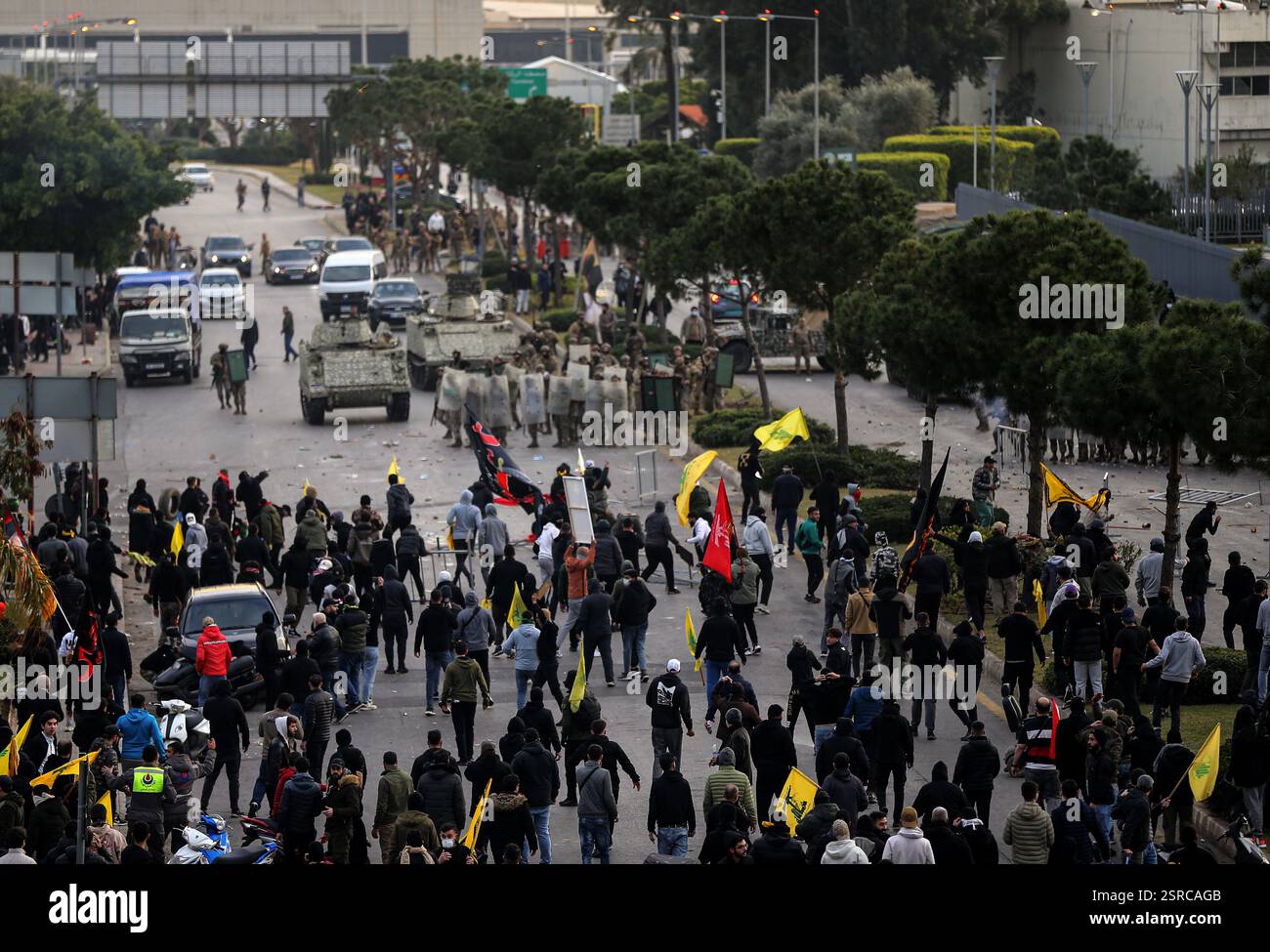 Beirut, Libano. 15 febbraio 2025. I manifestanti sventolano la bandiera di Hezbollah mentre affrontano i soldati dell'esercito libanese durante un raduno organizzato da Hezbollah che blocca la strada per l'aeroporto internazionale di Beirut, protestando contro la decisione di impedire l'atterraggio di due voli iraniani. Crediti: Marwan Naamani/dpa/Alamy Live News Foto Stock