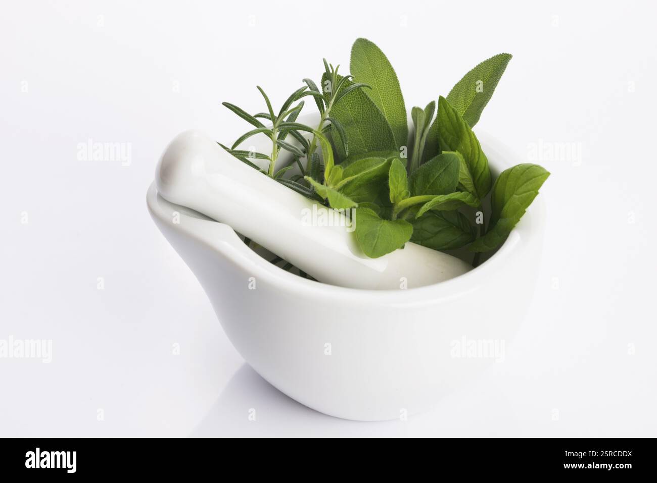 Mortaio con erbe isolate su fondo bianco Foto Stock