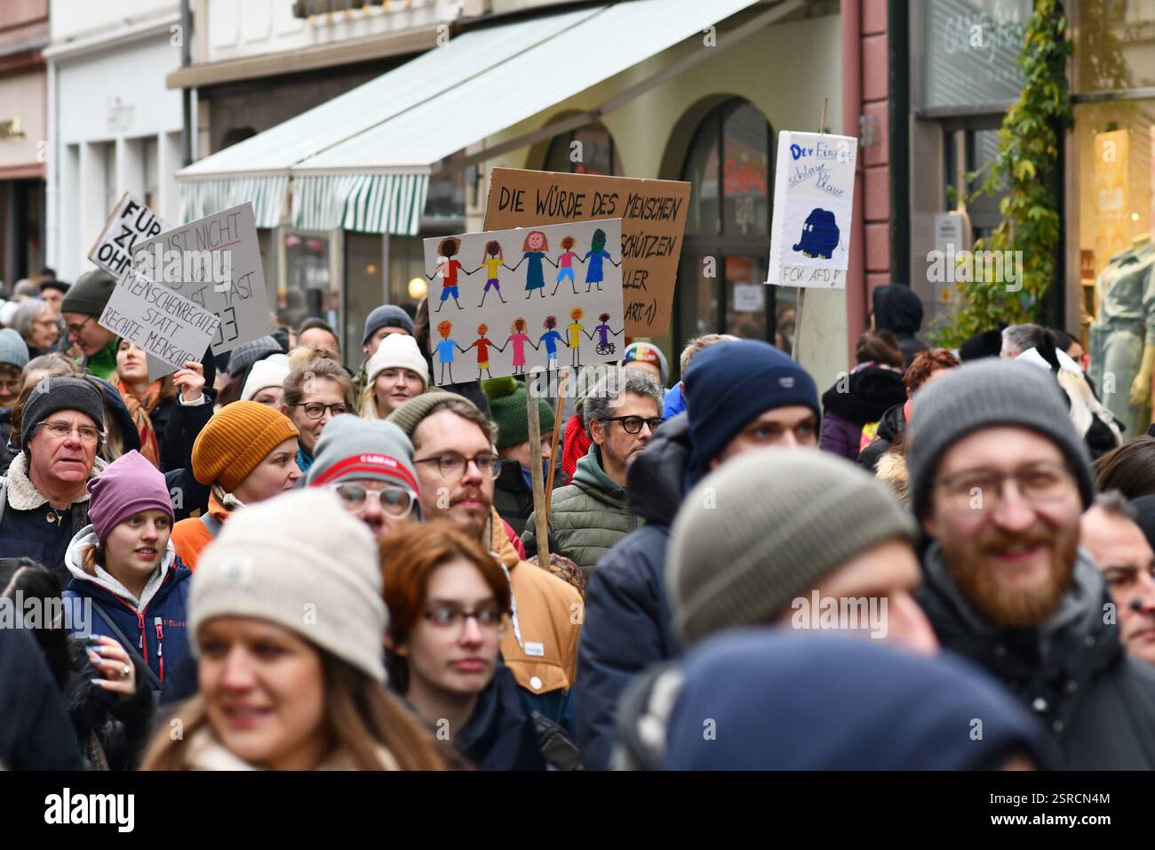 Heidelberg, Germania - 12 febbraio 2025: Persona che regge un cartello che mostra disegni di persone di colore in massa in protesta contro l'estrema destra Foto Stock