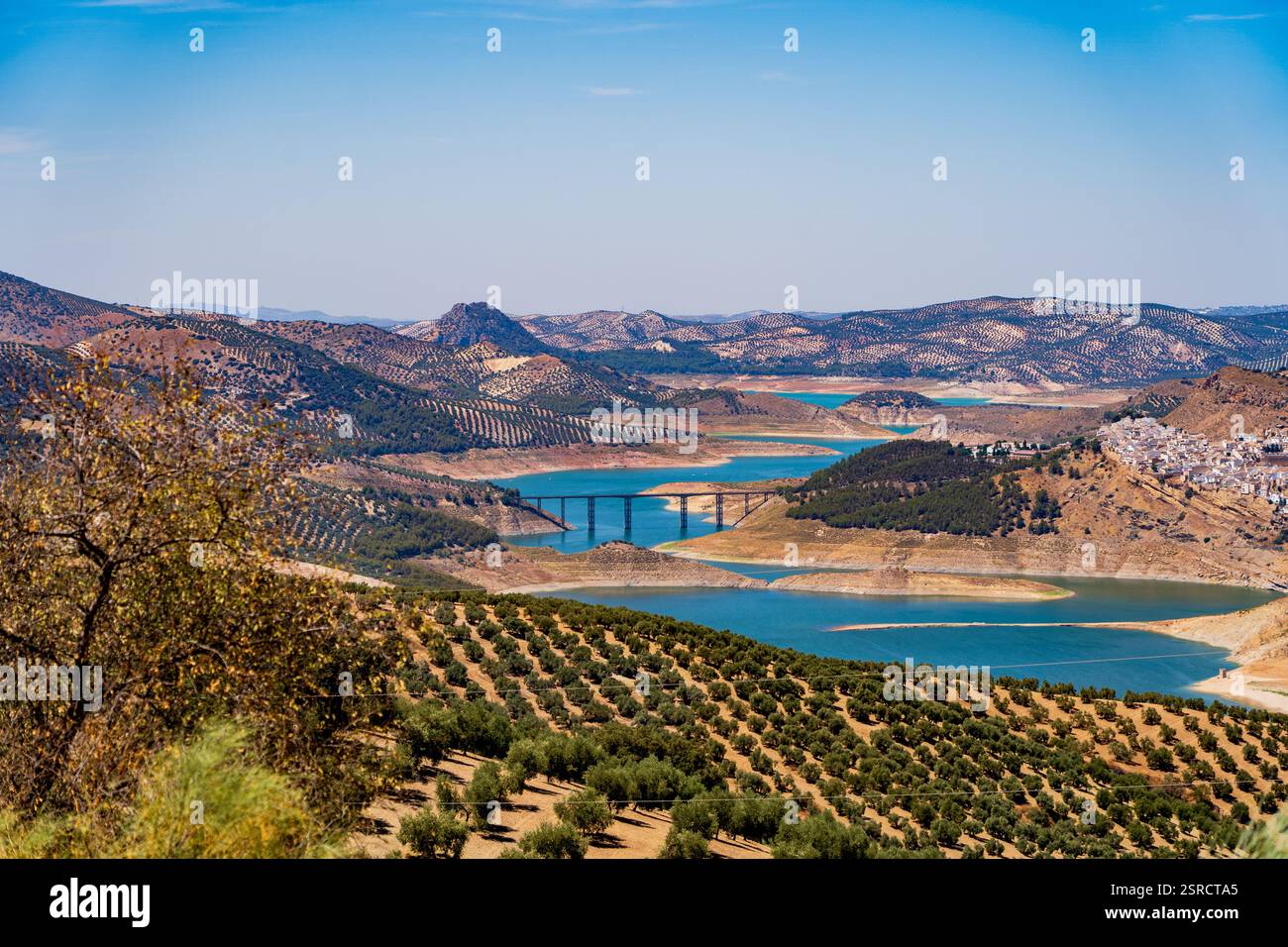 Ponte Agroman che collega Iznájar e gli oliveti circostanti sulle acque del Blue Reservoir nel paesaggio panoramico andaluso Foto Stock