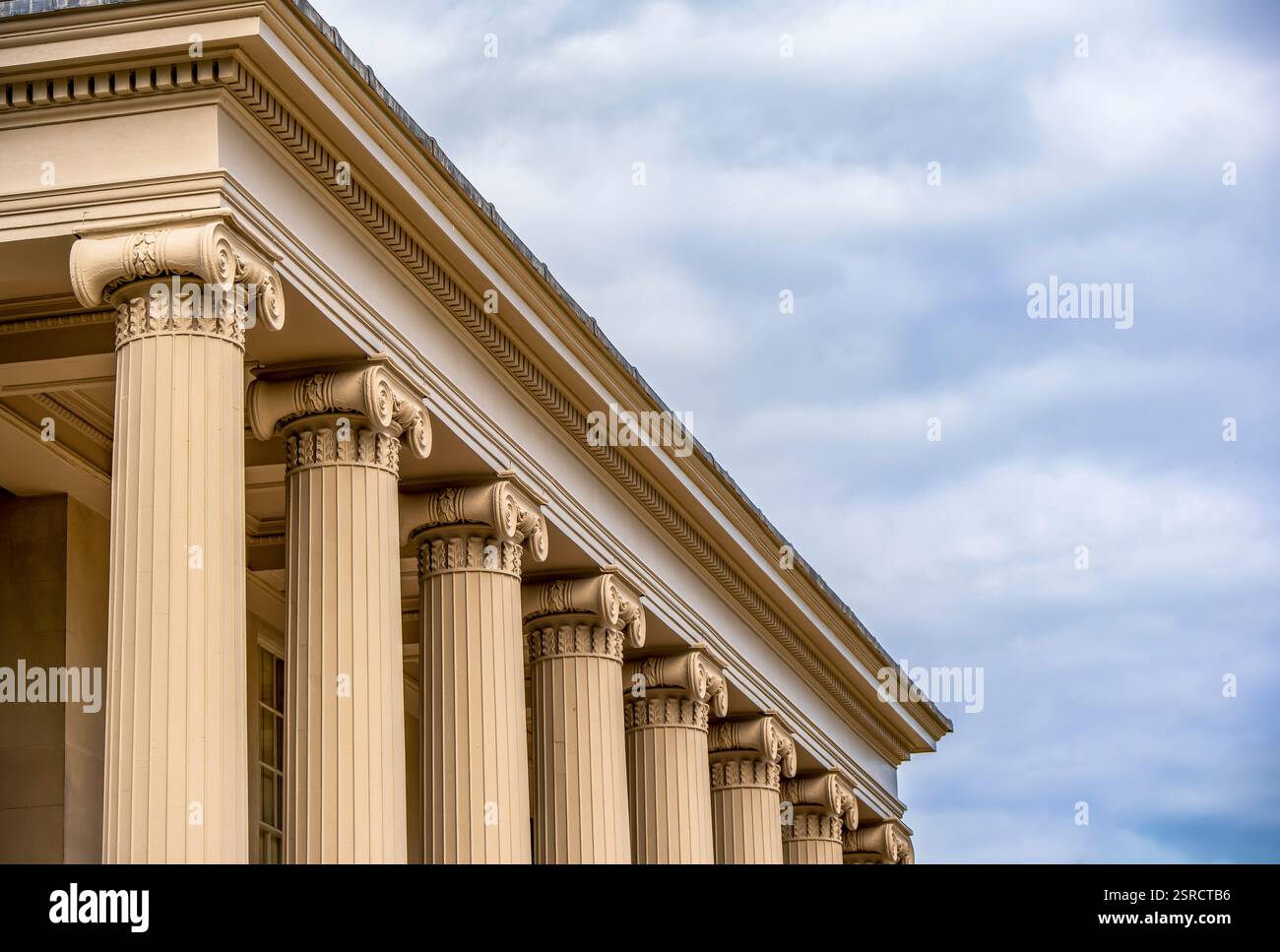 Colonne ioniche ornate che incarnano l'eleganza neoclassica sotto un cielo soffice Foto Stock