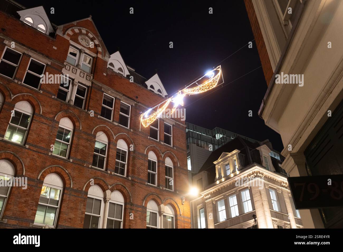 Luci natalizie ornate tra gli edifici di notte. Chancery Lane, City di Londra Foto Stock