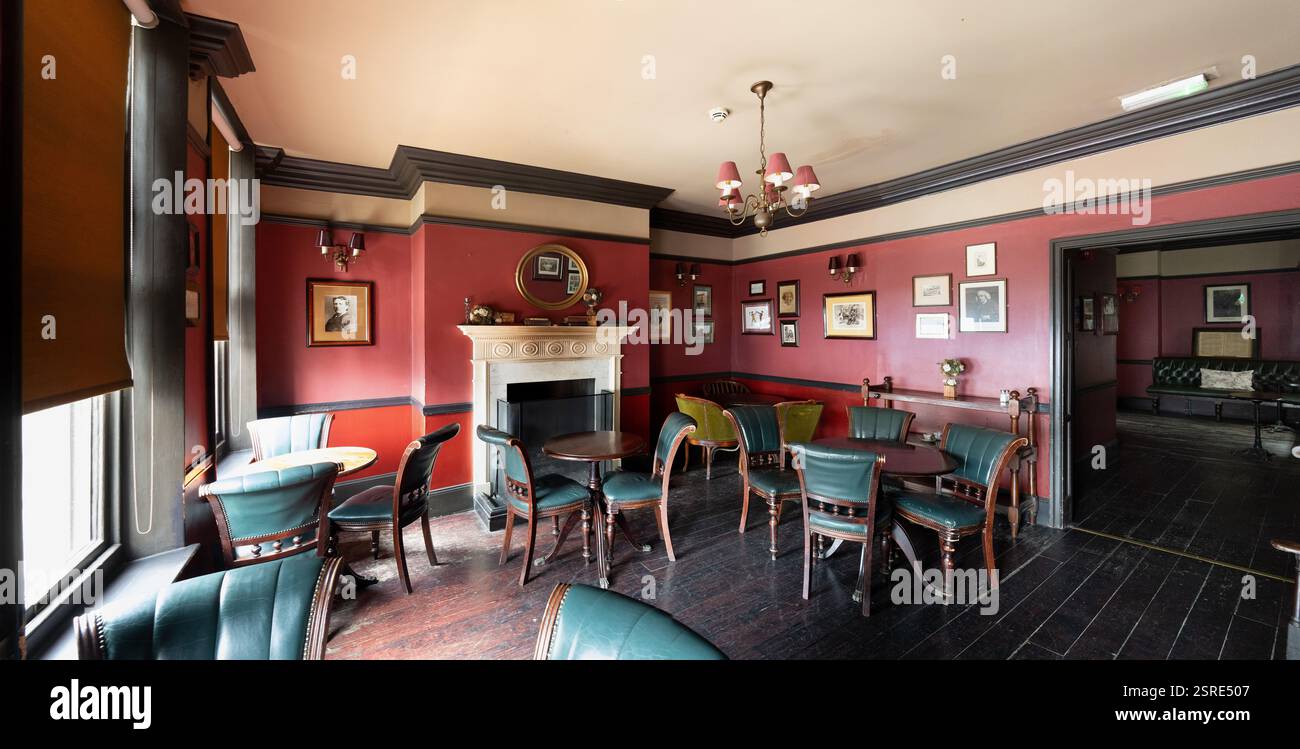 Accogliente interno del pub Ye Olde Cheshire Cheese. I clienti si rilassano ai tavoli, godendosi l'atmosfera. Foto storiche adornano le pareti. Foto Stock