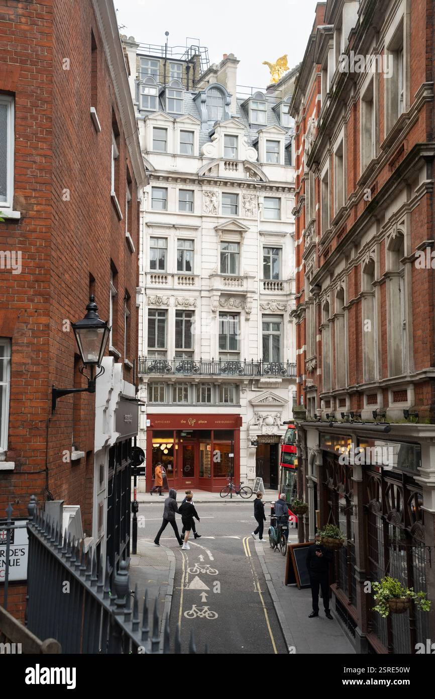 I pedoni attraversano una strada cittadina, i negozi fiancheggiano il vicolo stretto. Bride Lane, Fleet Street Foto Stock
