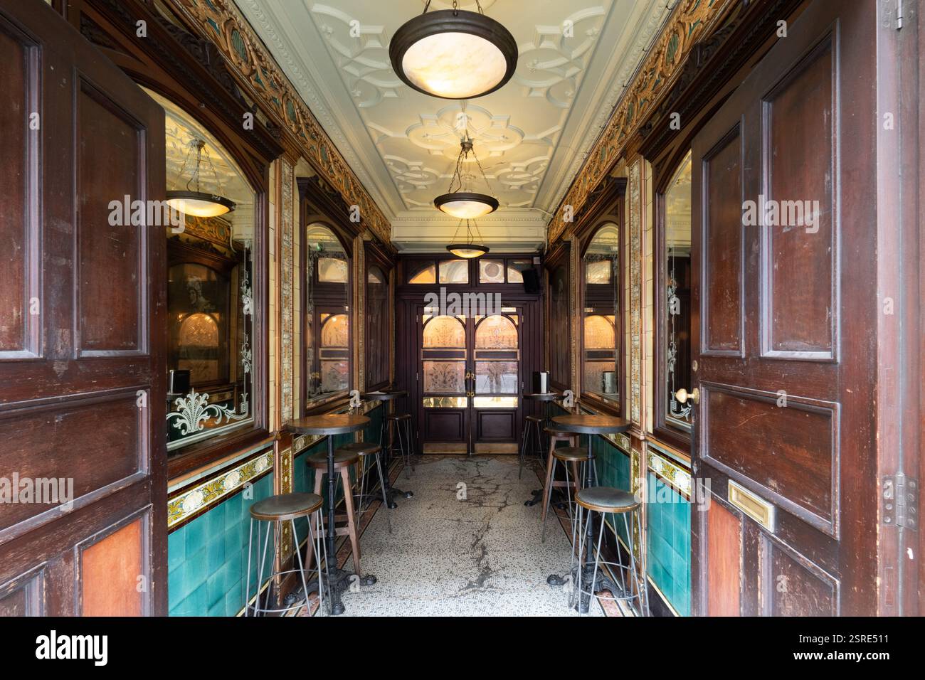 Ingresso al pub ornato. Tavoli da bar e sgabelli fiancheggiano il passaggio pedonale. Punch Tavern è un pub classificato Grade II al numero 98–100 Fleet Street Foto Stock