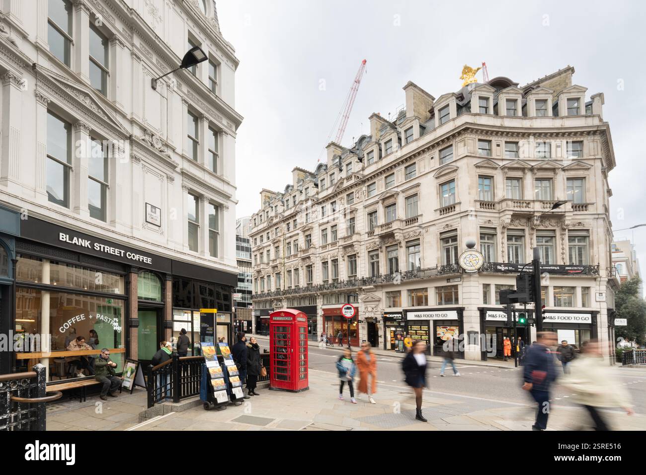 I pedoni attraversano una strada cittadina, oltrepassano Blank Street Coffee e M&S Food To Go, a Londra. Ludgate Circus Foto Stock