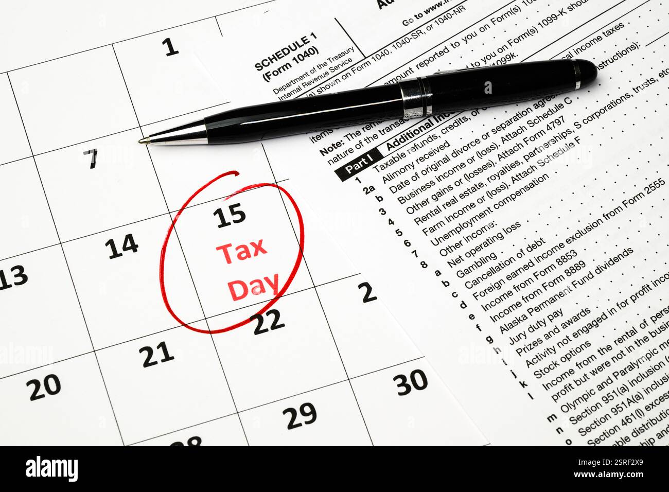 Giorno delle imposte cerchiato con inchiostro rosso nel calendario del mese con penna nera e modulo fiscale 1040 Foto Stock