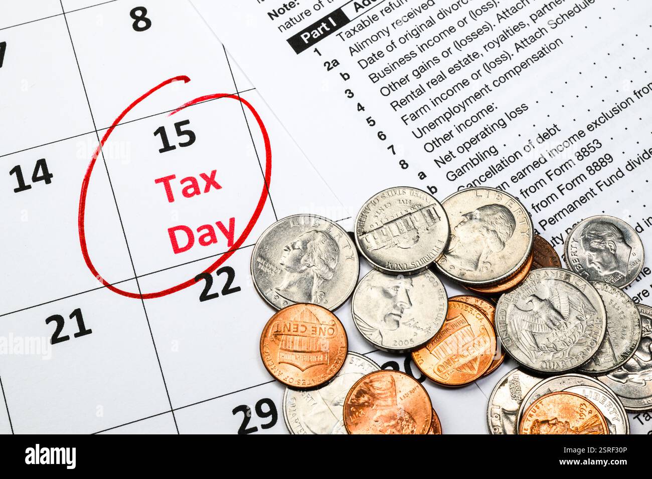 Giorno delle imposte 15 aprile cerchiato in inchiostro rosso sul calendario con pile di monete e modulo di tassazione Foto Stock