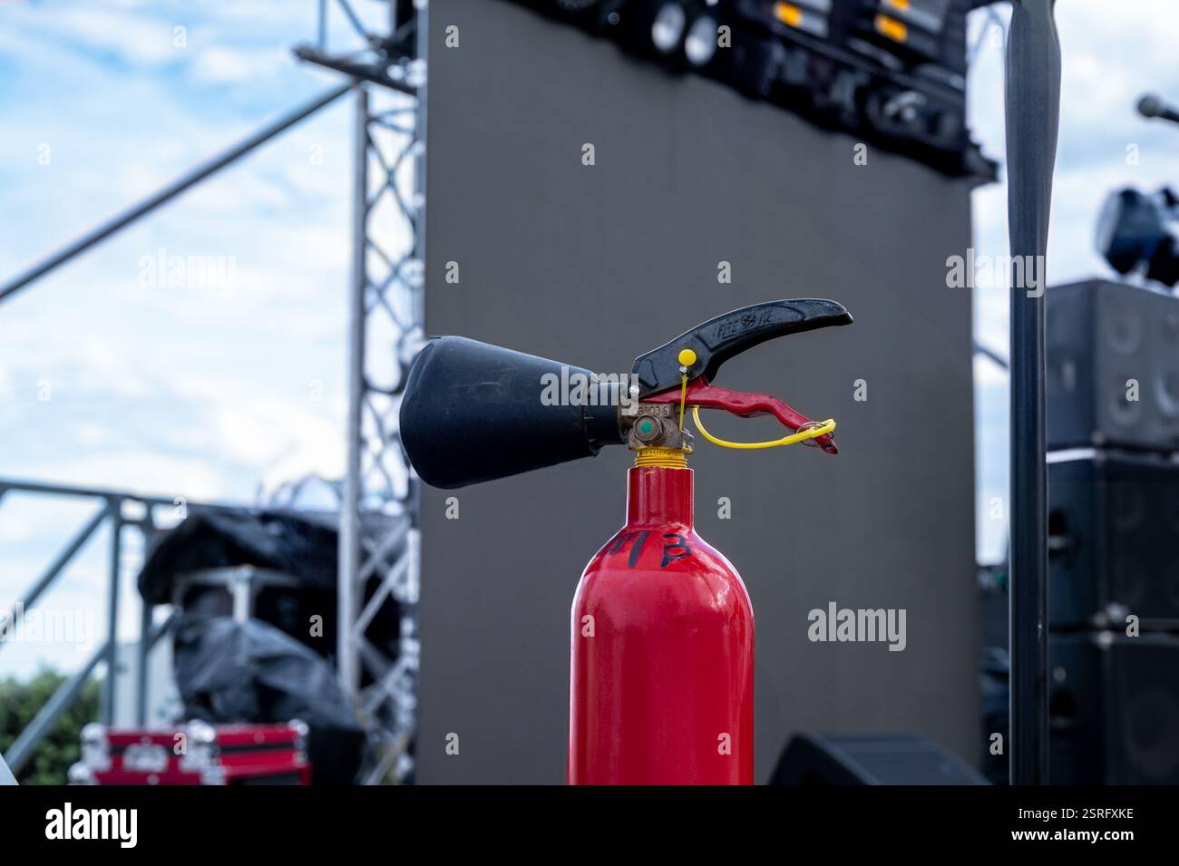 Un estintore rosso si trova su un'asta metallica. Il palo fa parte di un palcoscenico allestito per un concerto Foto Stock