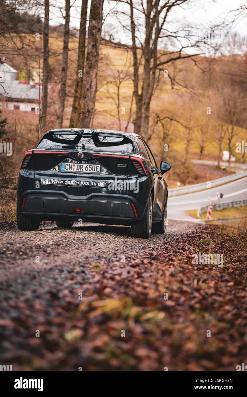 Auto nera che guida su una strada rurale e tortuosa autunnale, condivisione di e-car, Deer Mobility, MG4, Calw, Germania, Europa Foto Stock